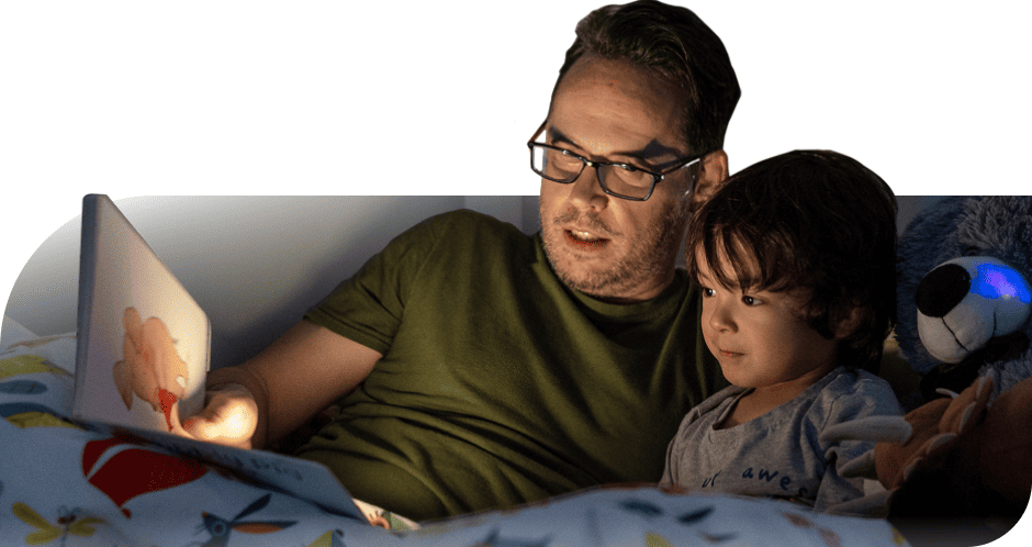 Father reading a bedtime story to his child under dim light